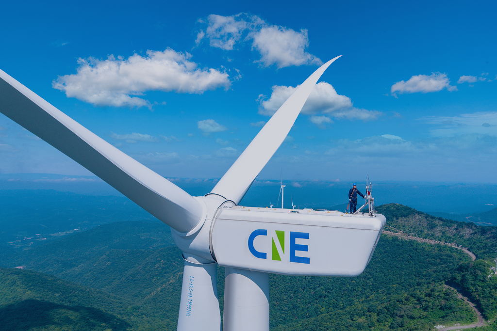 Windmill with CNE's logo with a background of blue sky and green landscape