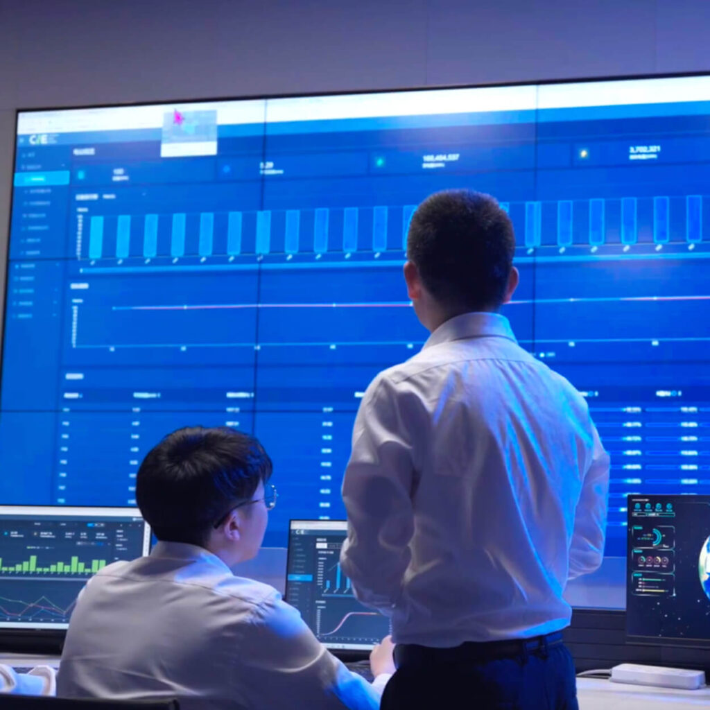 Two analysts looking at blue screen filled with data