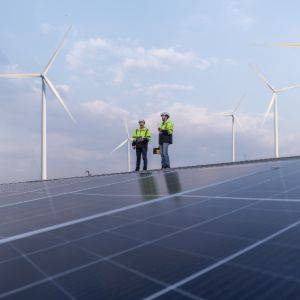 Technicians inspect solar panels and wind turbines.
