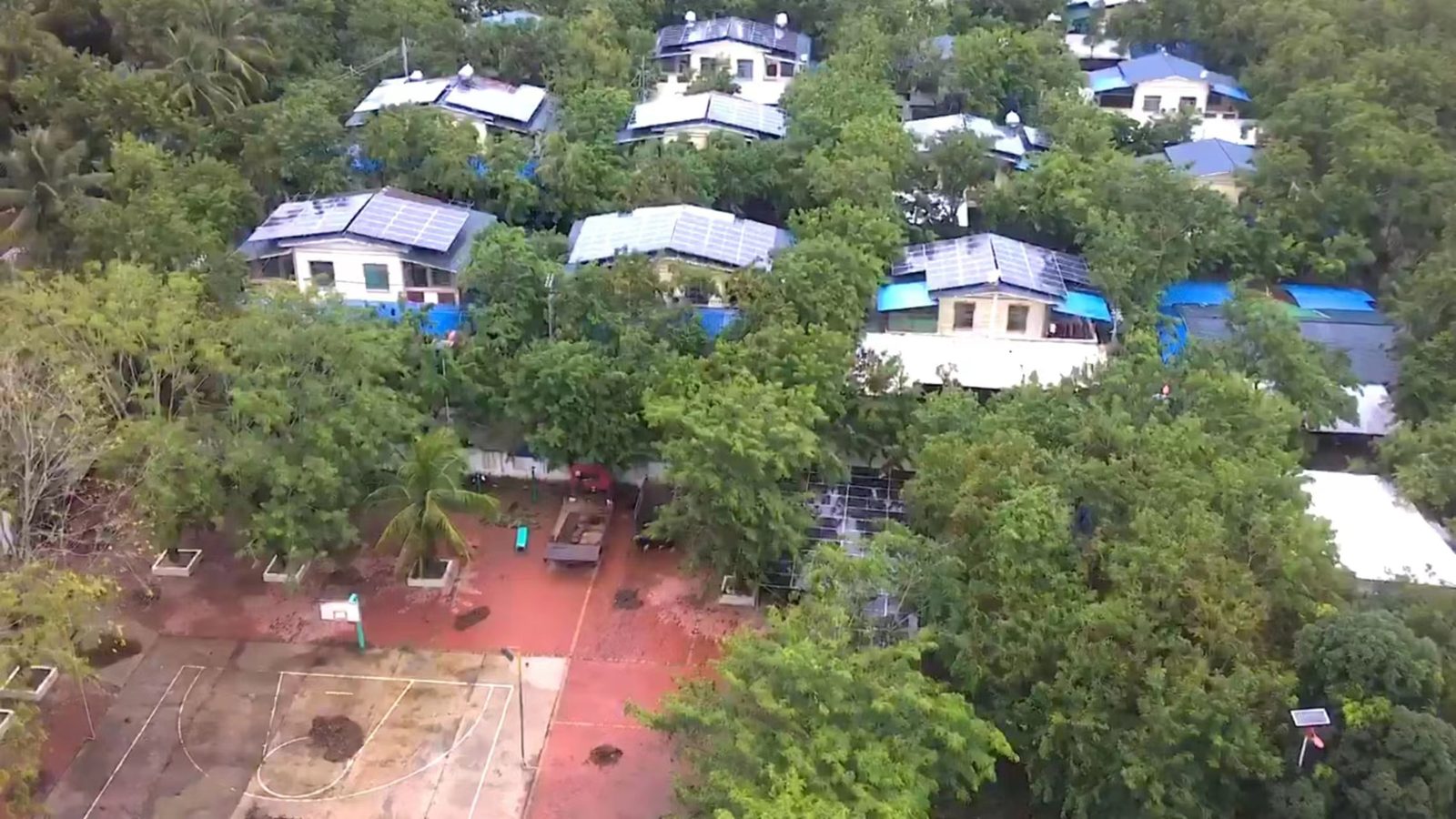 Aerial view of village homes with rooftop solar panels among trees, part of CNE's household rooftop PV project in Dongfang, Hainan
